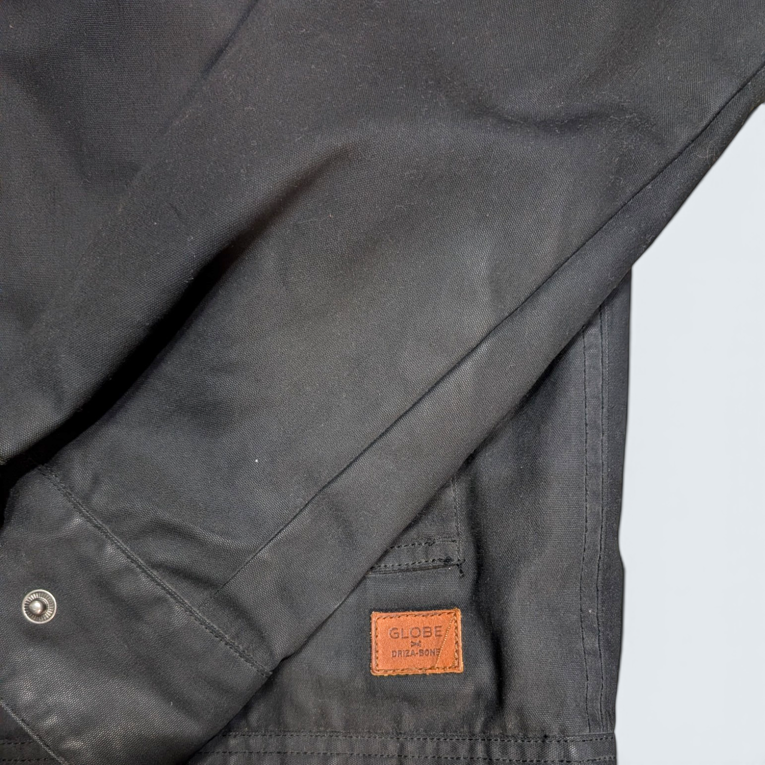 Close-up of a dark gray jacket with a brown leather label on a light gray background