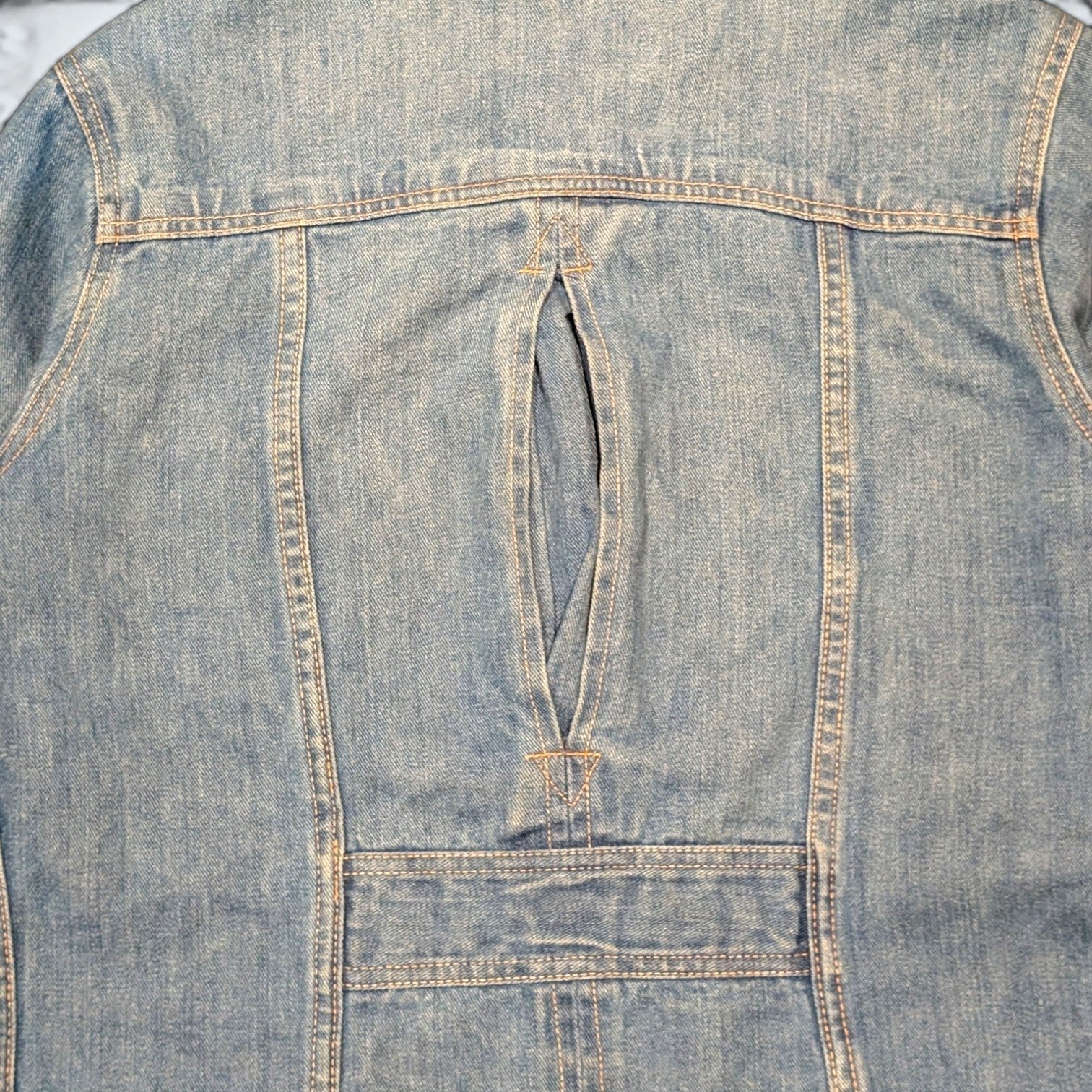 Back view of STOXX THRIFT & VINTAGE Britannia Sportswear light-wash denim jacket featuring a unique back vent detail.
