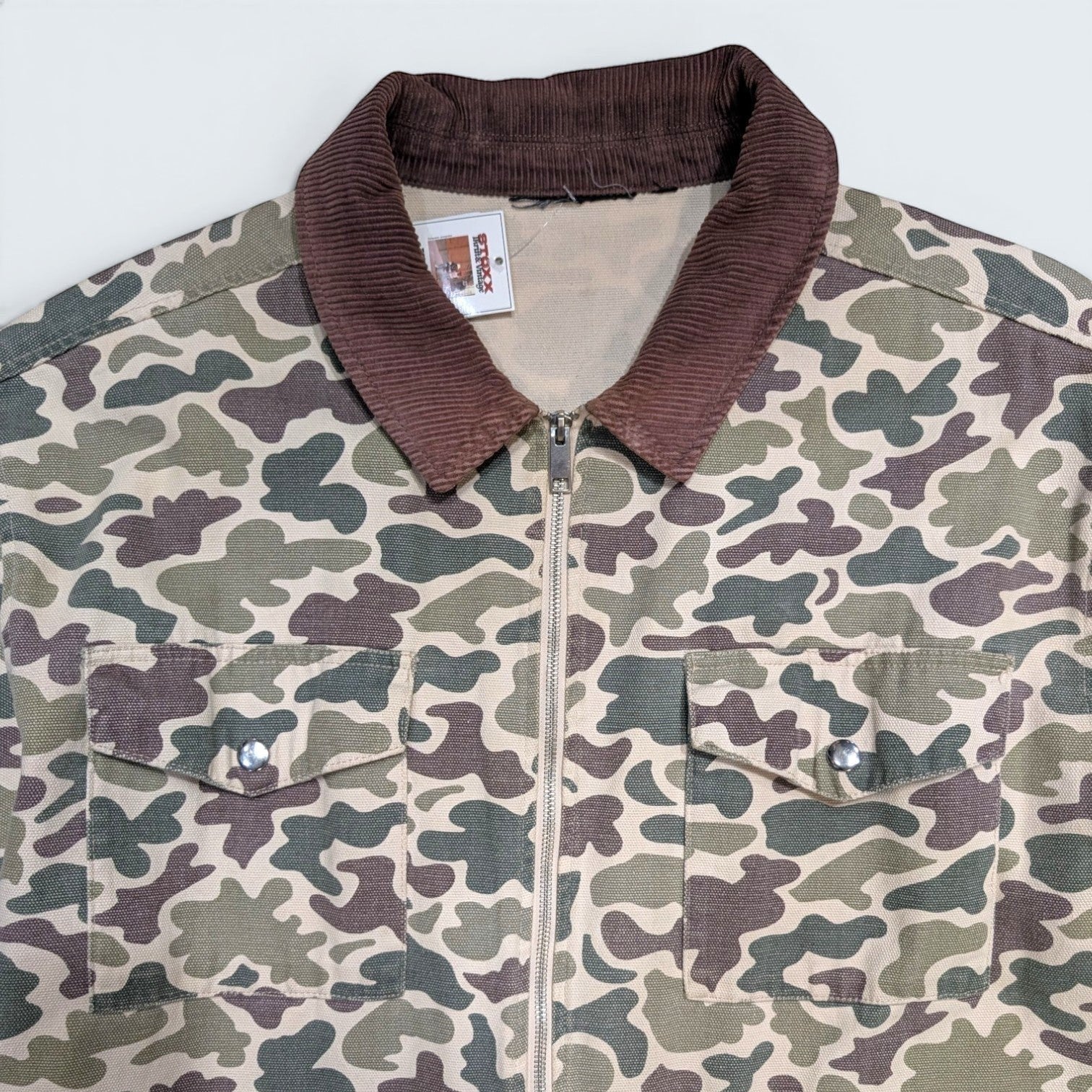 STOXX THRIFT & VINTAGE camo print chore jacket with a brown corduroy collar, zip front, and two chest pockets.