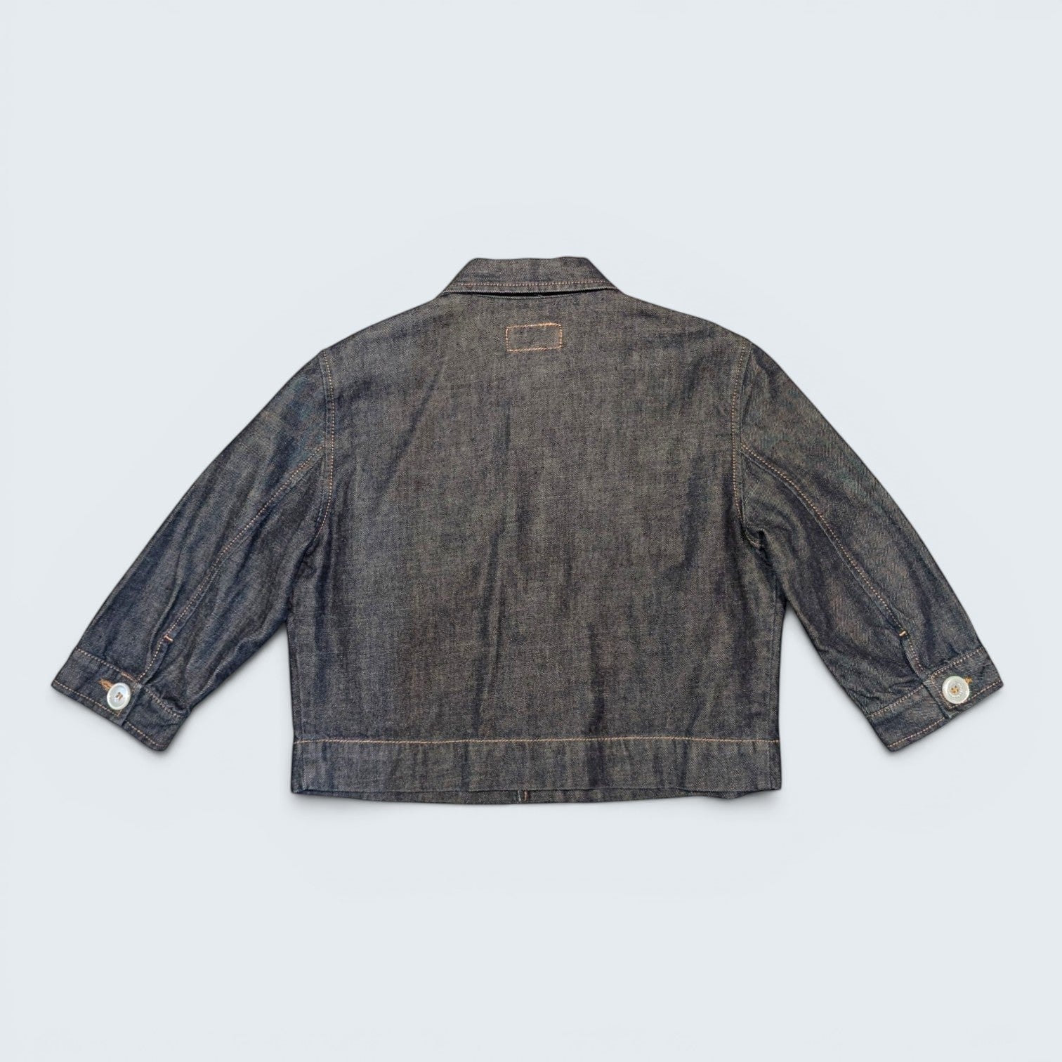Back view of a dark wash denim jacket by STOXX THRIFT & VINTAGE with button cuffs and classic collar.