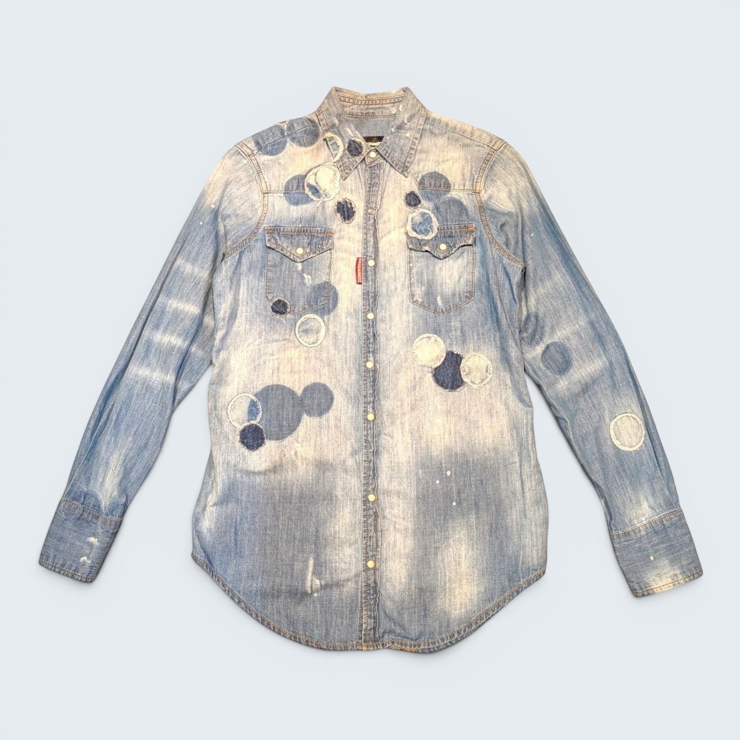 STOXX THRIFT & VINTAGE DSQUARED2 light wash denim shirt with circular patchwork, paint splatters, and button-down front.