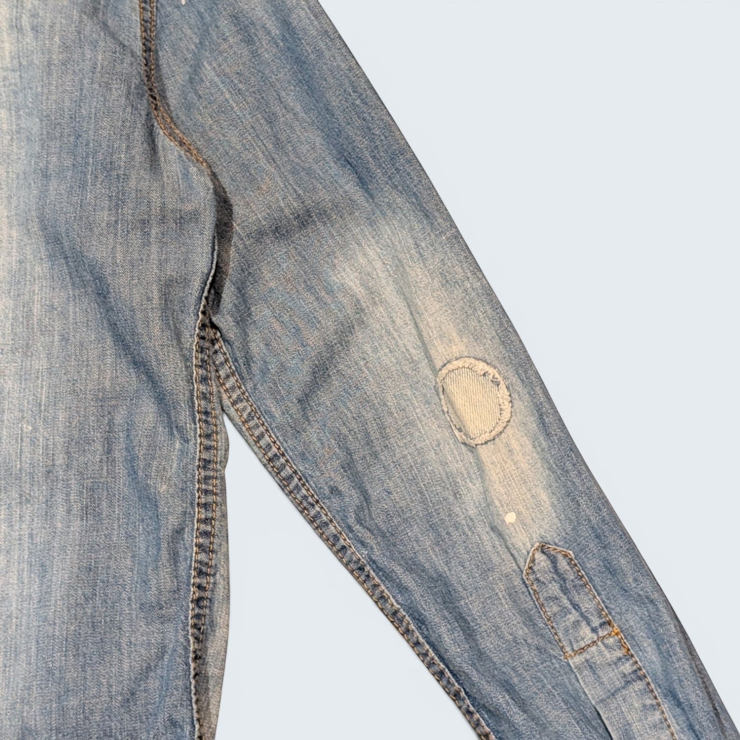 STOXX THRIFT & VINTAGE DSQUARED2 light wash denim shirt sleeve with circular patchwork and distressed paint details.