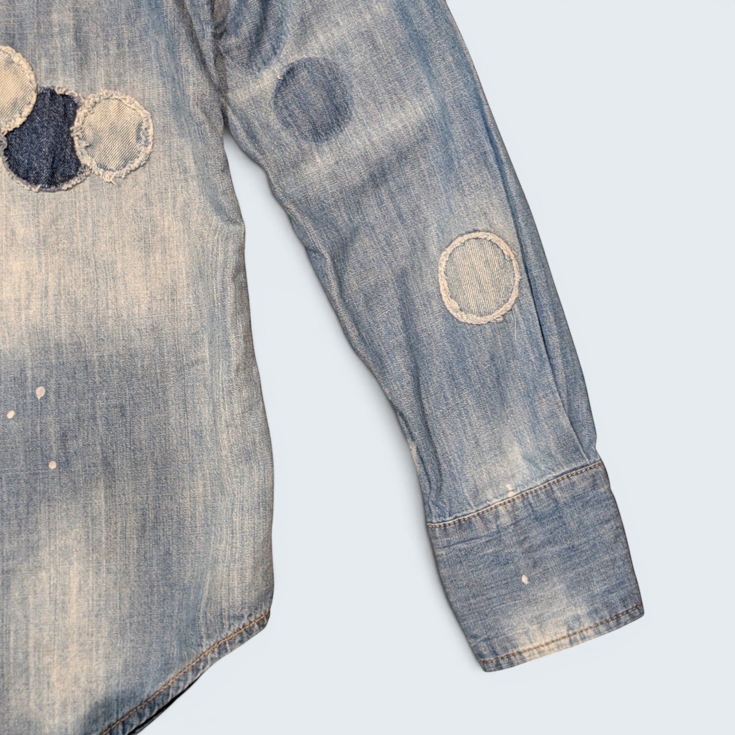 STOXX THRIFT & VINTAGE DSQUARED2 light wash denim shirt featuring circular patchwork, paint splatters, and frayed edges.