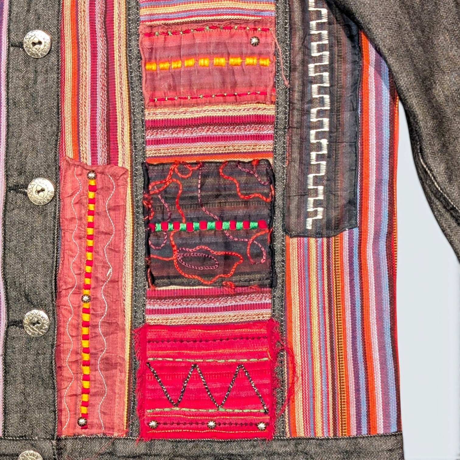 STOXX THRIFT & VINTAGE Attitude denim jacket featuring colorful bohemian embroidered patches and striped fabric panels.