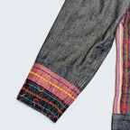 STOXX THRIFT & VINTAGE dark wash denim jacket sleeve with colorful embroidered trim and pink fabric cuff detail.