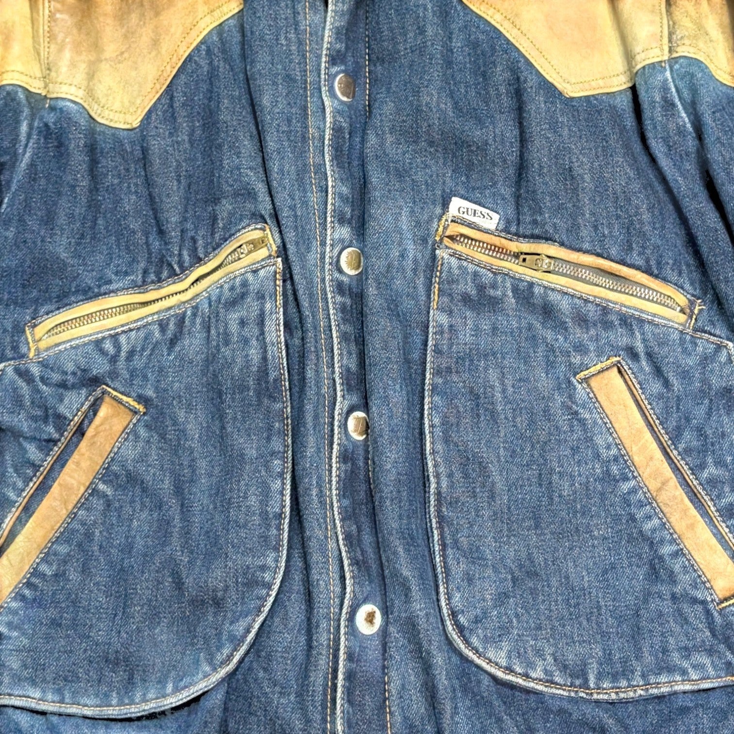STOXX THRIFT & VINTAGE Guess blue denim jacket with tan leather western yoke and zippered pockets.