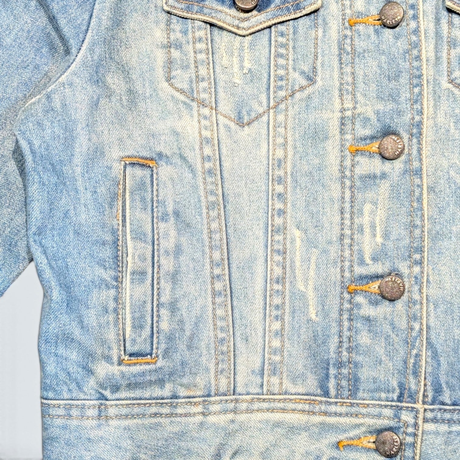 STOXX THRIFT & VINTAGE light wash Harley Davidson denim jacket with distressed details and branded metal buttons.