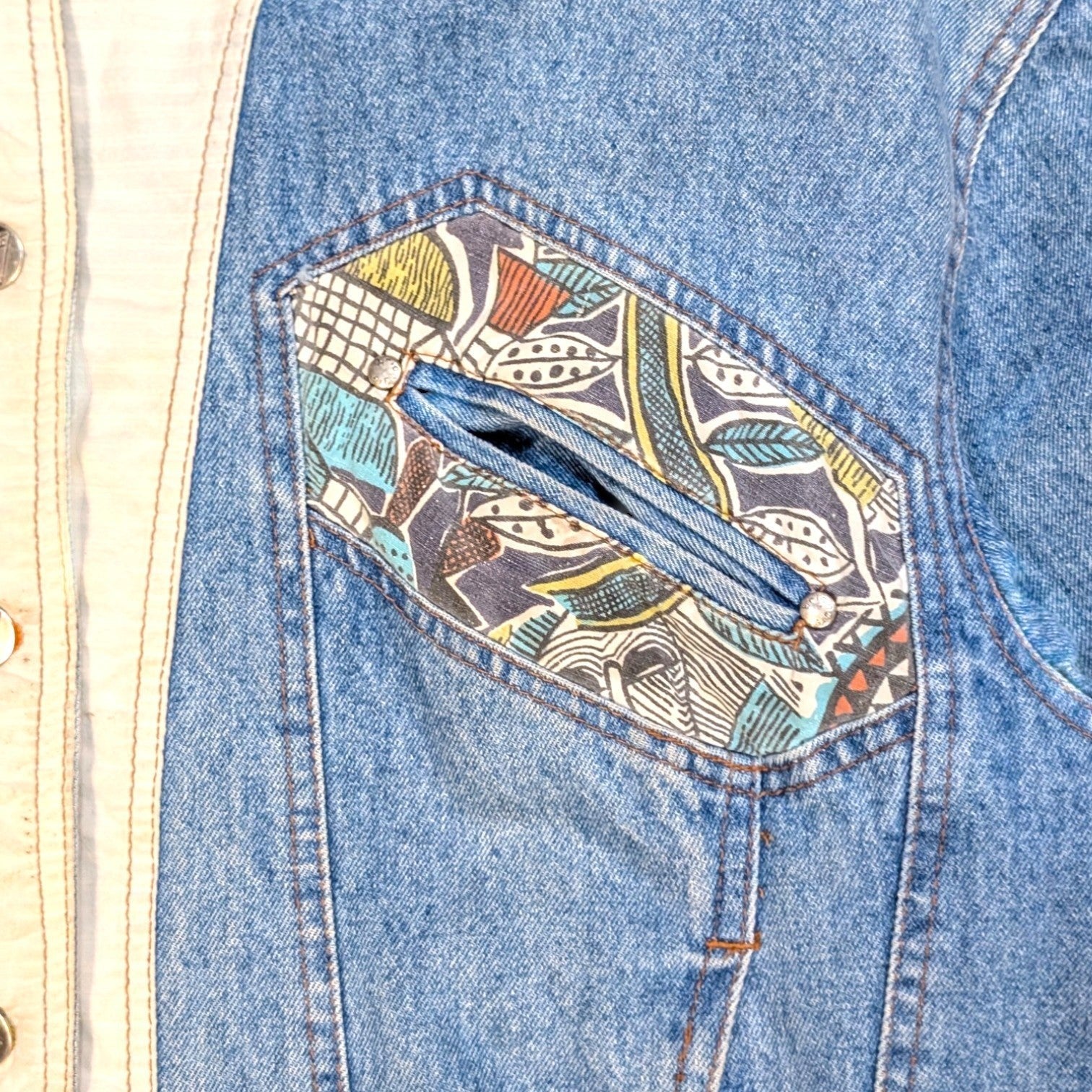 STOXX THRIFT & VINTAGE blue denim jacket featuring a unique jungle-patterned patch pocket and cream trim detail.