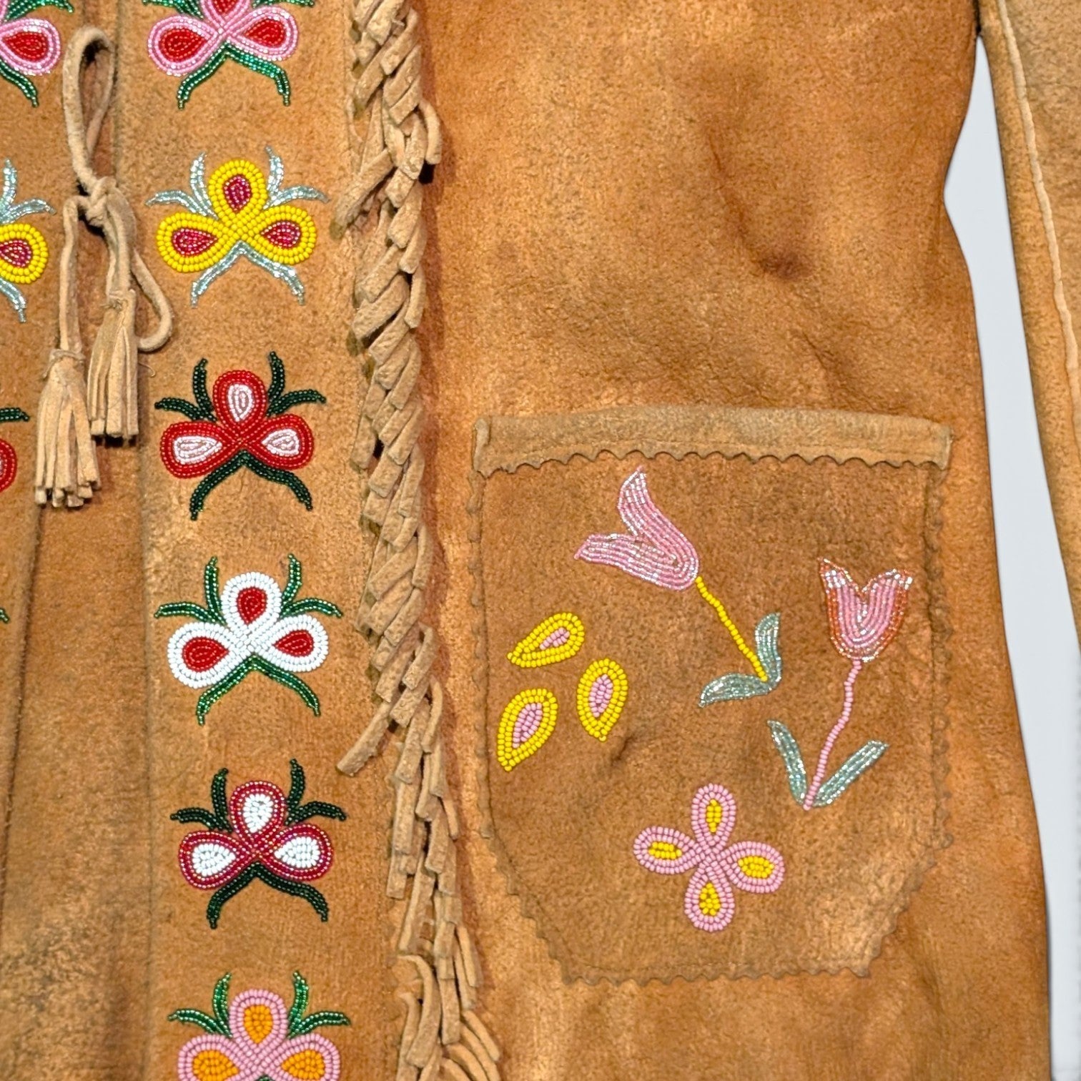 STOXX THRIFT & VINTAGE tan suede jacket with hand-sewn beaded floral patterns, fringe trim, and tassel tie closure.