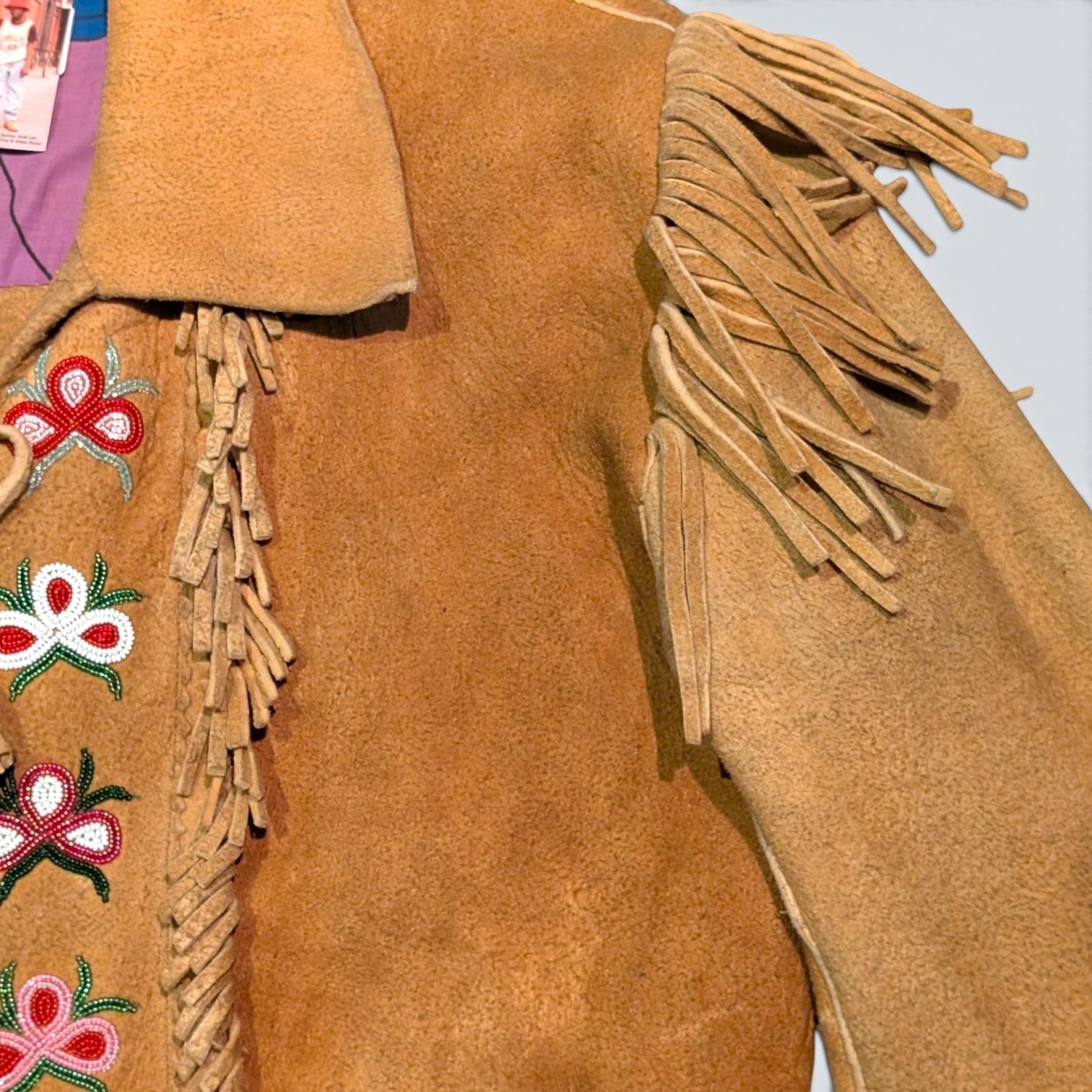 STOXX THRIFT & VINTAGE tan suede jacket with hand-sewn beaded floral patterns and fringe detailing on the shoulders.